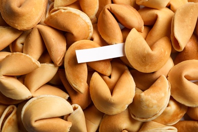 Photo of Paper with prediction on pile of fortune cookies, top view