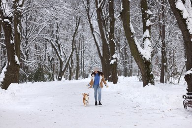 Photo of Woman with adorable Pembroke Welsh Corgi dog running in snowy park