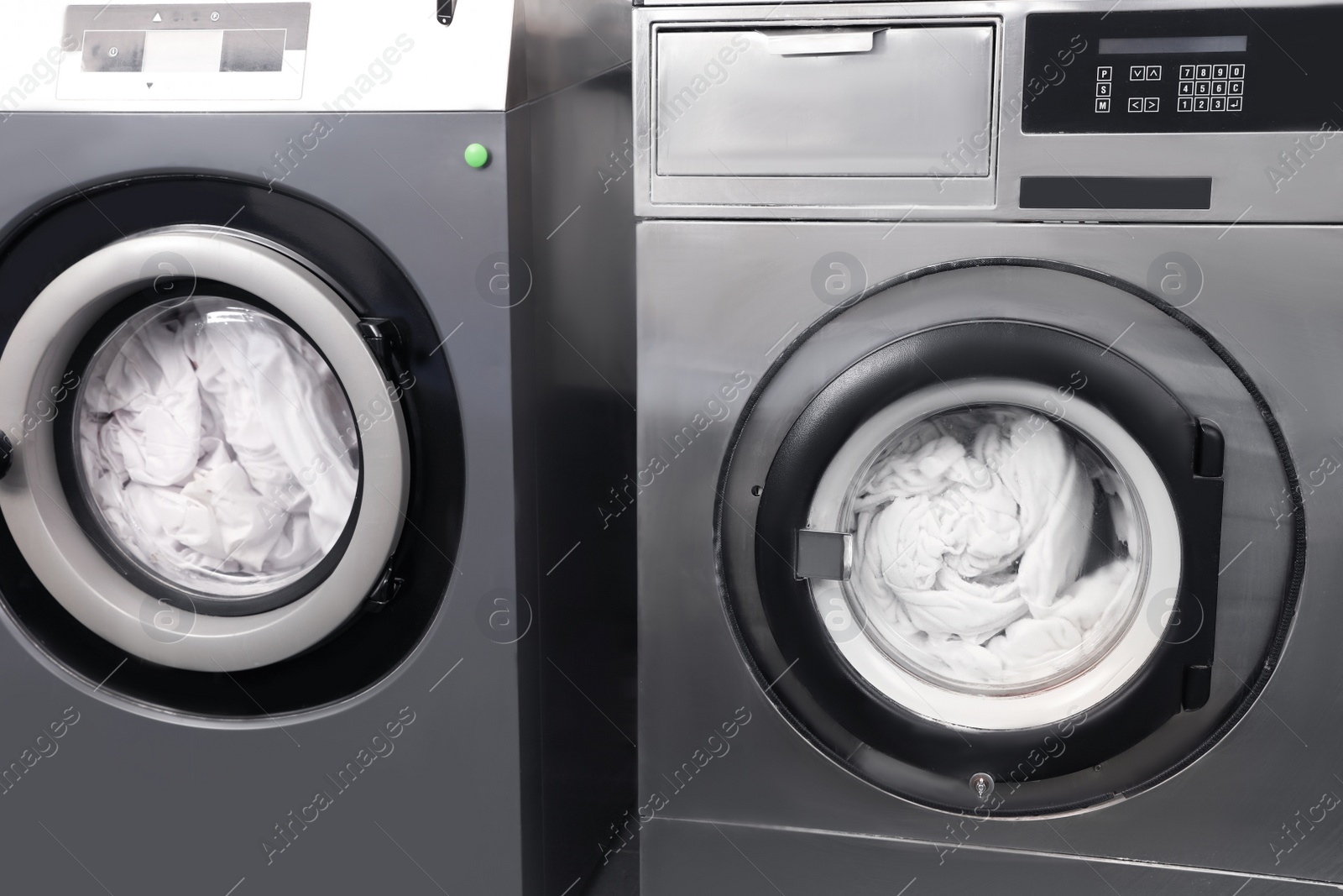 Photo of Pair of washing machines with laundry in dry-cleaning, closeup