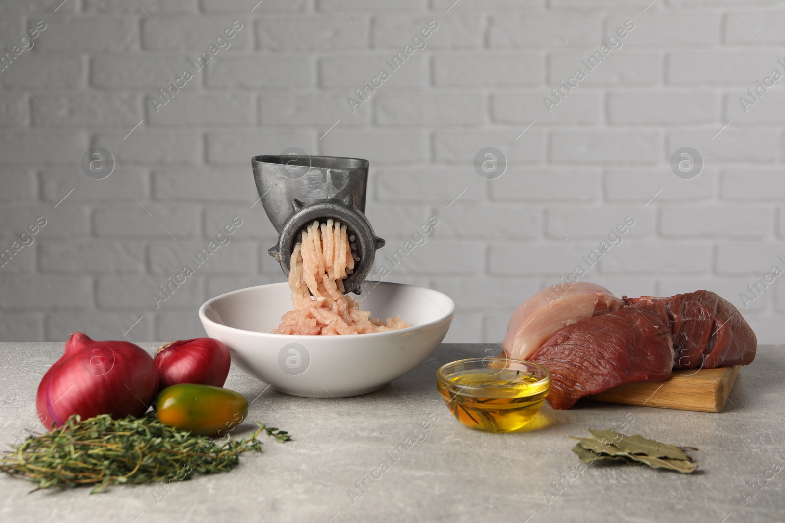 Photo of Metal meat grinder with chicken mince and different products on light grey table