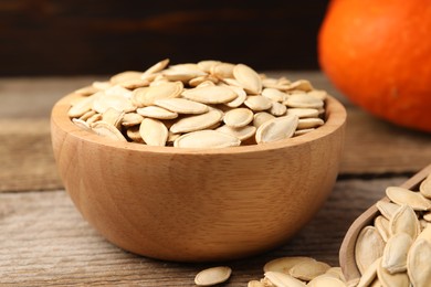 Photo of Bowl with pumpkin seeds on wooden table, closeup