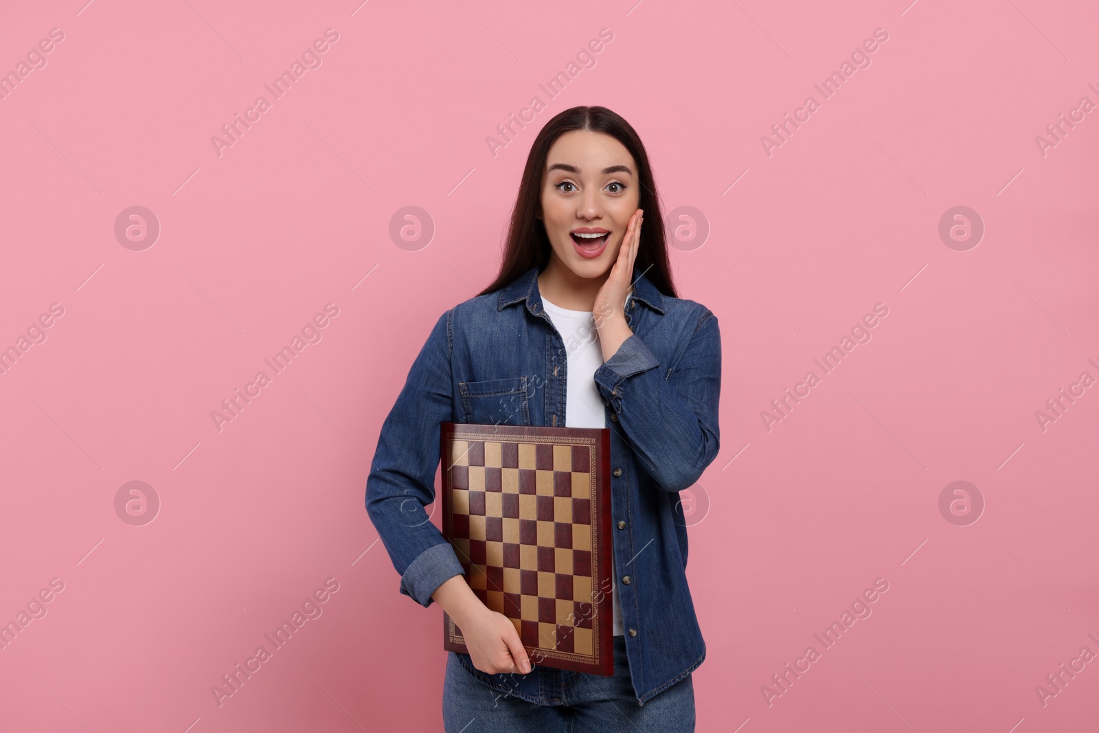 Photo of Happy woman with chessboard on pink background