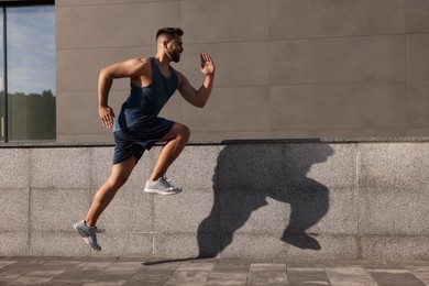 Young man running near building outdoors. Space for text