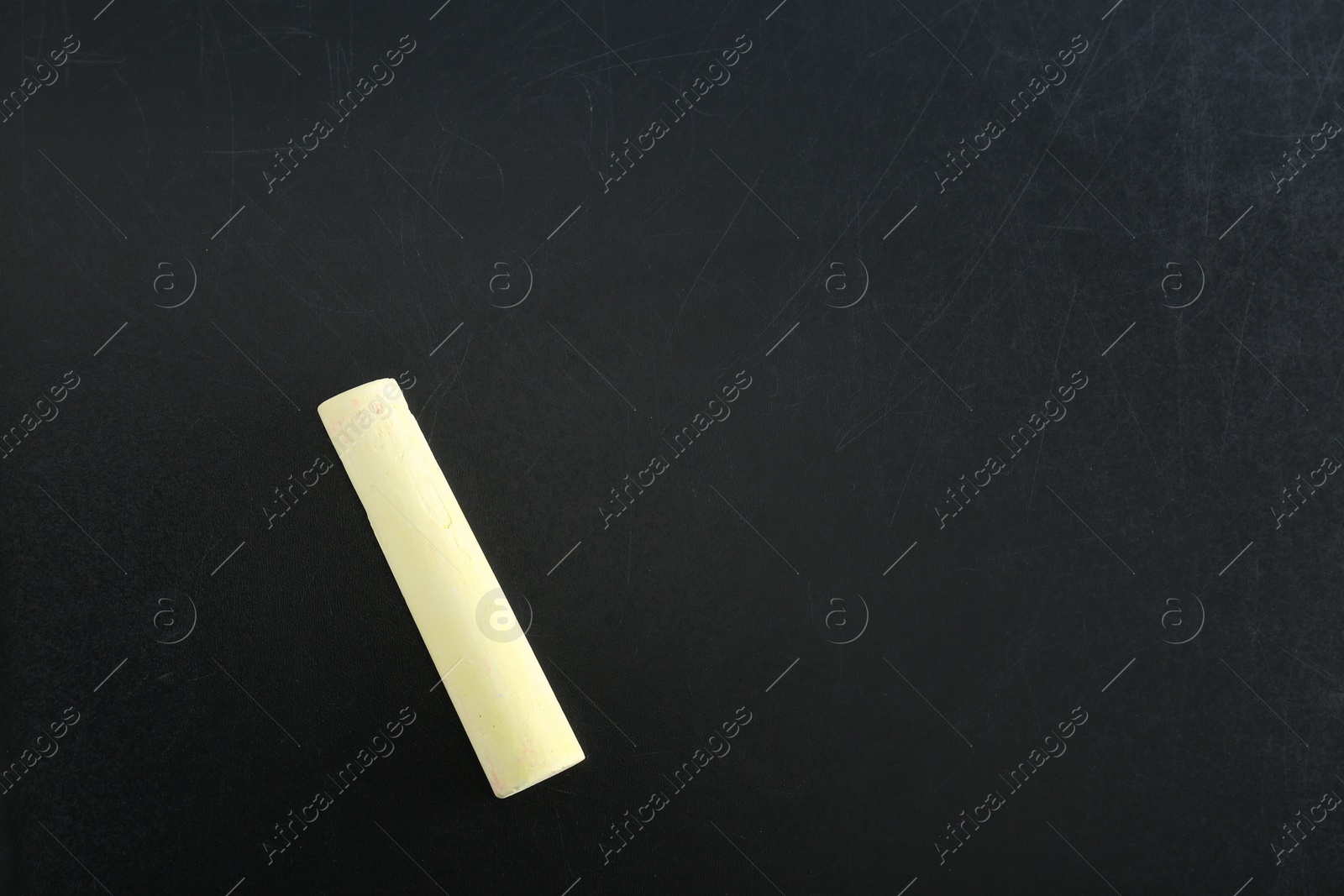 Photo of Yellow piece of chalk on blackboard, top view