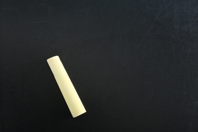 Photo of Yellow piece of chalk on blackboard, top view