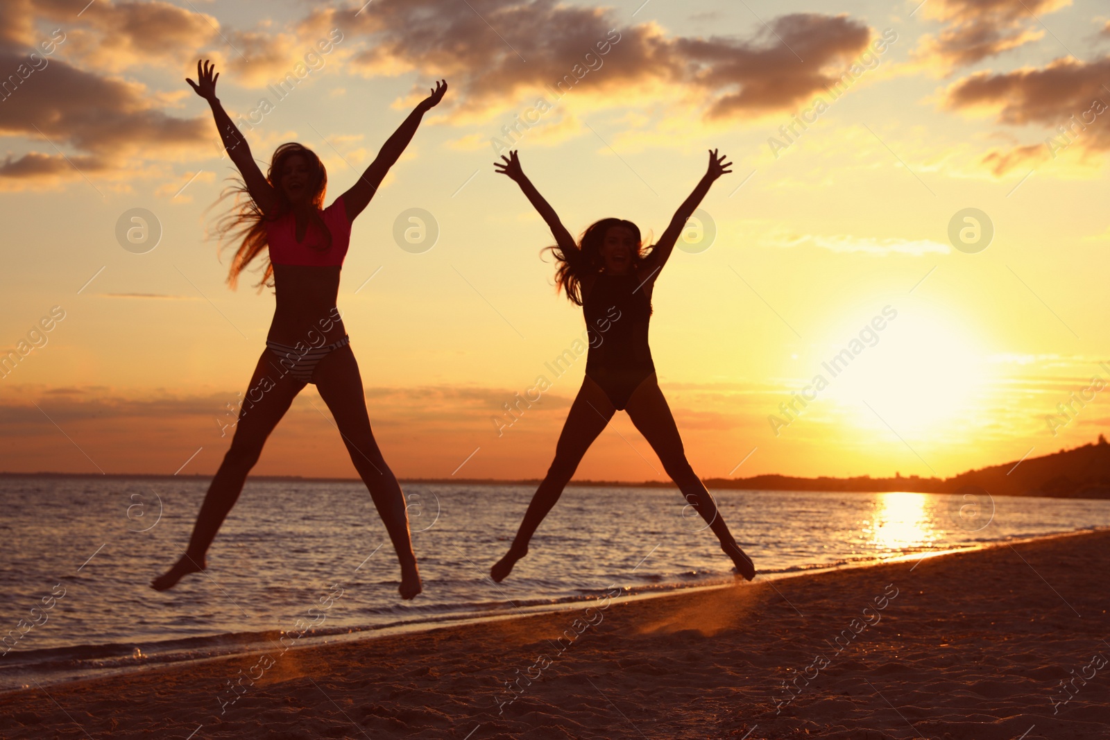 Photo of Young woman in bikini with girlfriend on beach. Lovely couple