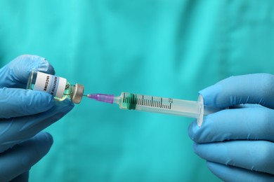 Doctor filling syringe with hepatitis vaccine from glass vial, closeup