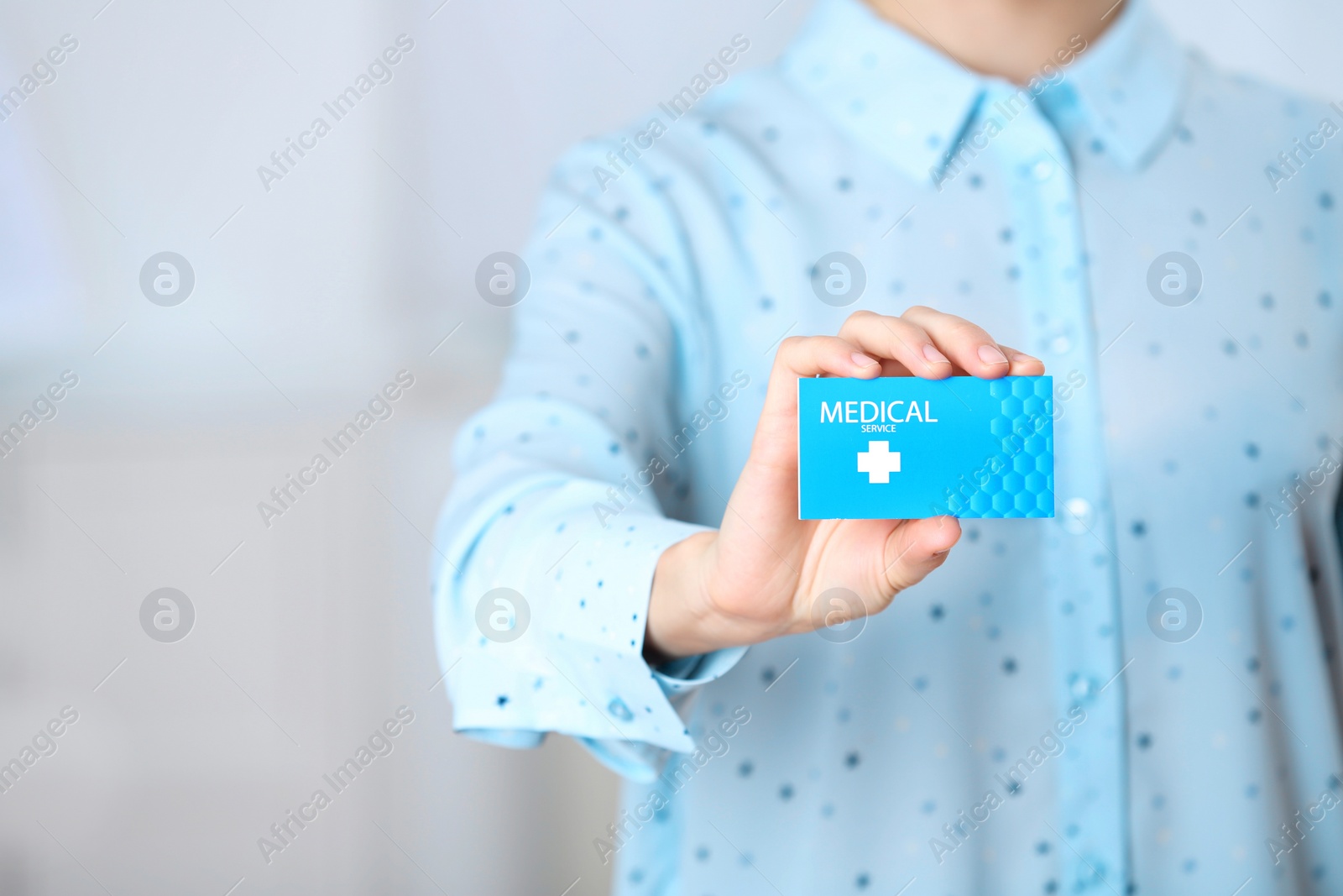 Photo of Woman holding business card indoors, closeup with space for text. Medical service