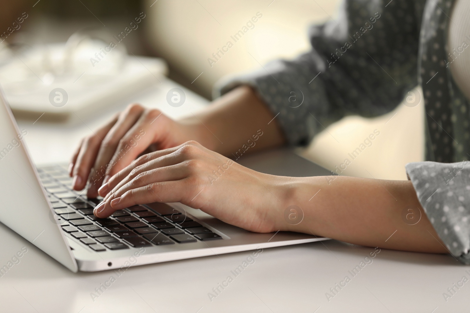 Photo of Woman working with laptop at white table indoors, closeup