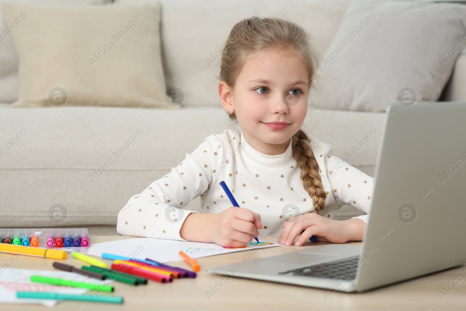 Photo of Little girl drawing with felt-tip pen following online course at home. Time for hobby