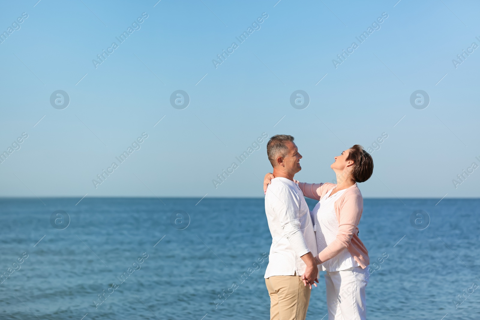 Photo of Happy mature couple holding hands at beach on sunny day