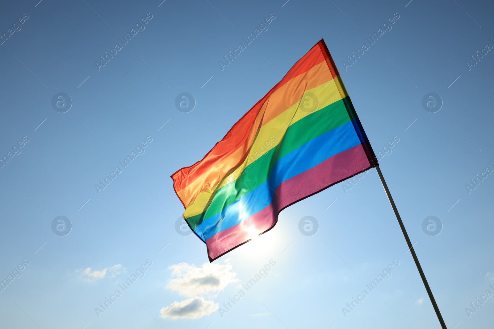 Photo of Bright LGBT flag fluttering against blue sky, space for text. Lesbian concept