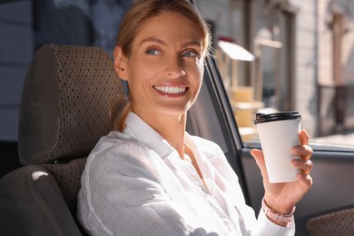 Coffee to go. Happy woman with paper cup of drink in car