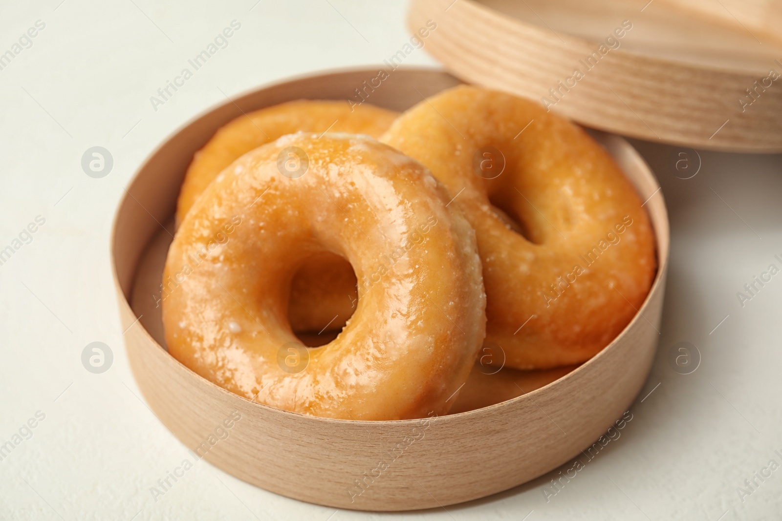 Photo of Sweet delicious glazed donuts on white table, closeup