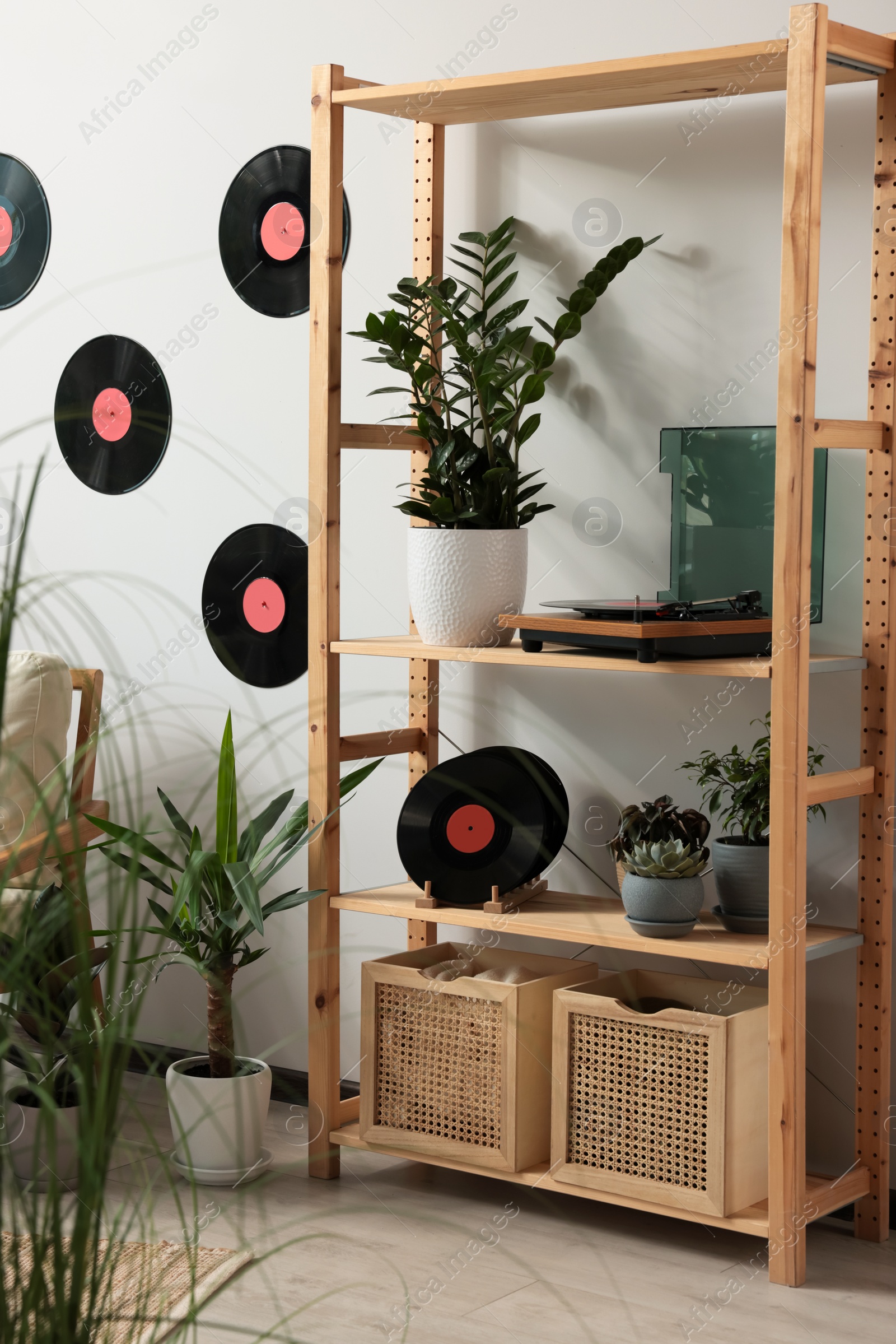 Photo of Room interior with stylish turntable on wooden shelving unit and vinyl records