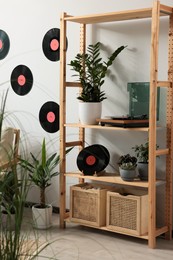 Room interior with stylish turntable on wooden shelving unit and vinyl records