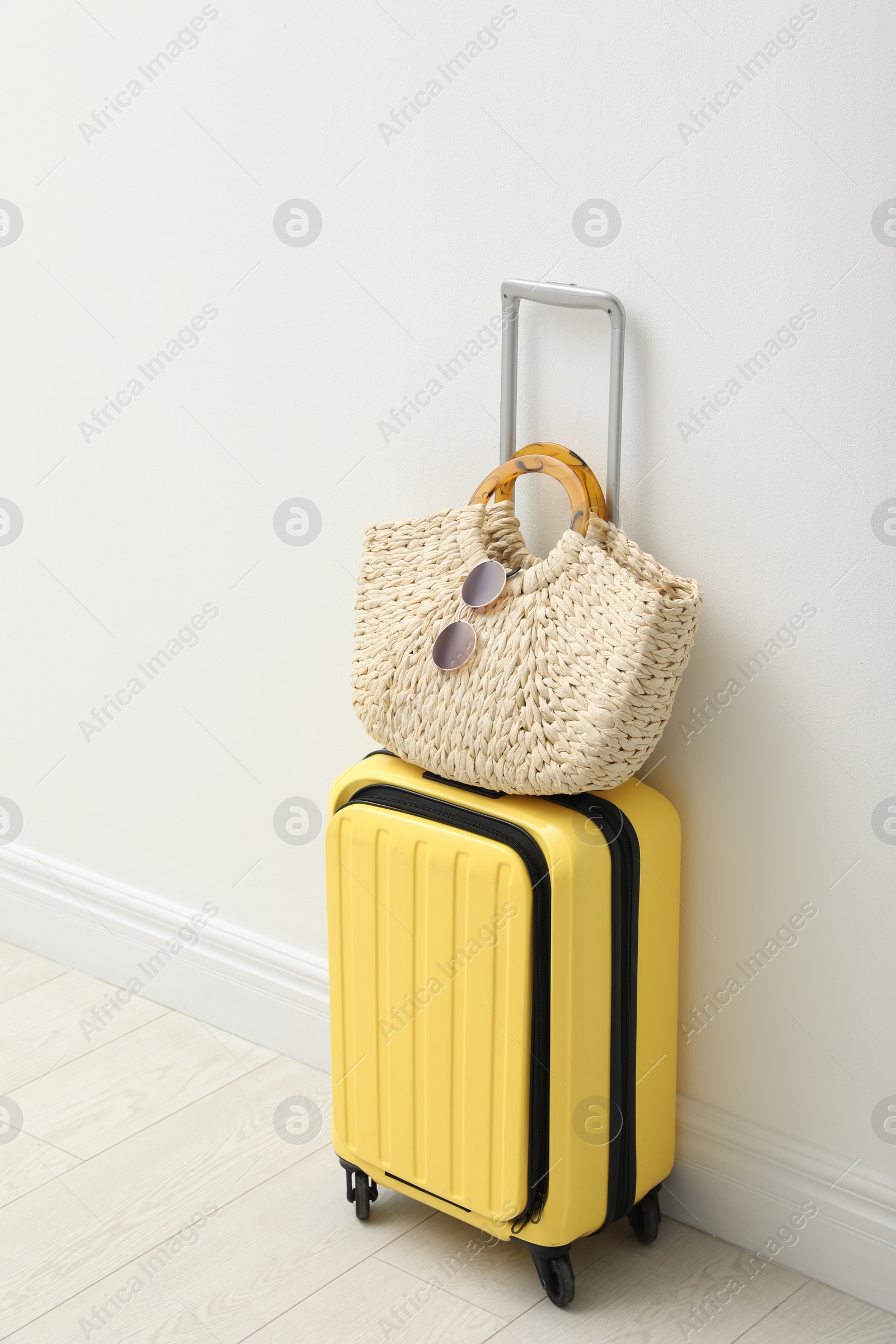 Photo of Suitcase packed for trip and summer accessories near white wall indoors
