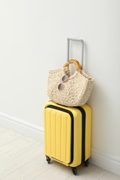 Suitcase packed for trip and summer accessories near white wall indoors