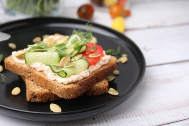 Tasty vegan sandwich with cucumber, tomato and pumpkin seeds on white wooden table, closeup. Space for text