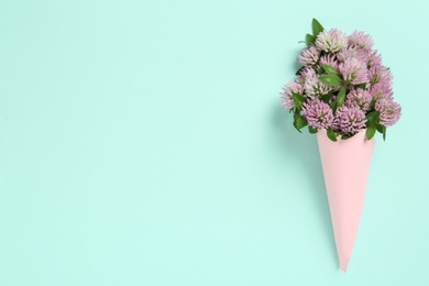 Photo of Bouquet of beautiful clover flowers on turquoise background, top view. Space for text