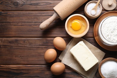 Photo of Making shortcrust pastry. Rolling pin and different ingredients for dough on wooden table, flat lay. Space for text