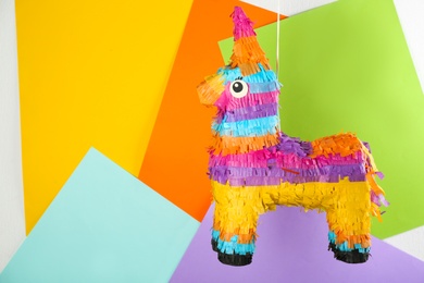 Photo of llama shaped pinata hanging on color background. Space for text