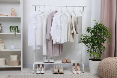 Rack with different stylish women`s clothes and shoes indoors