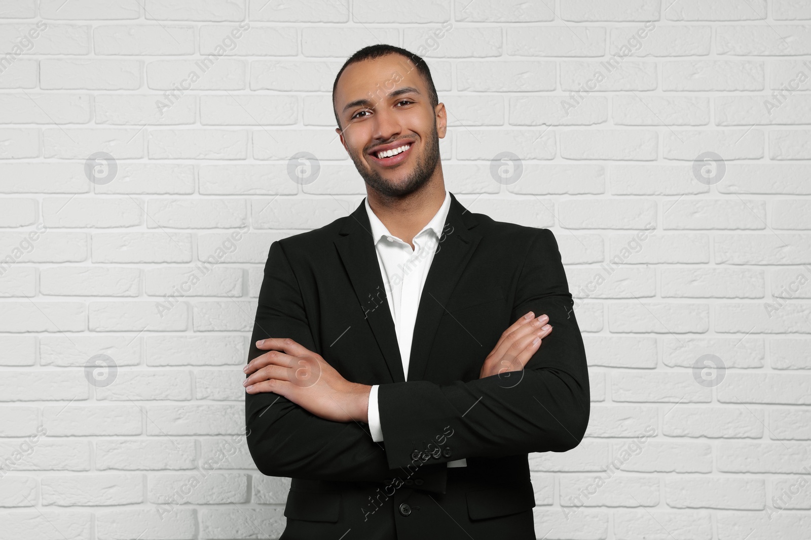 Photo of Young businessman in formal outfit near white brick wall