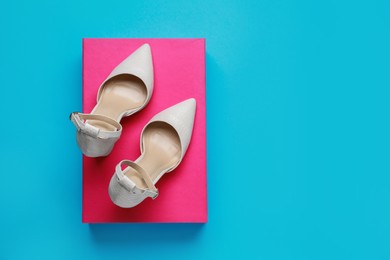 Stylish women's shoes with cardboard box on light blue background, top view. Space for text