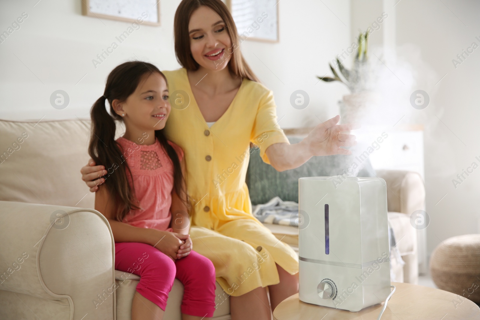 Photo of Mother and daughter near modern air humidifier at home