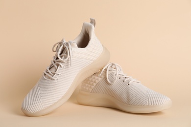 Photo of Pair of stylish sport shoes on beige background