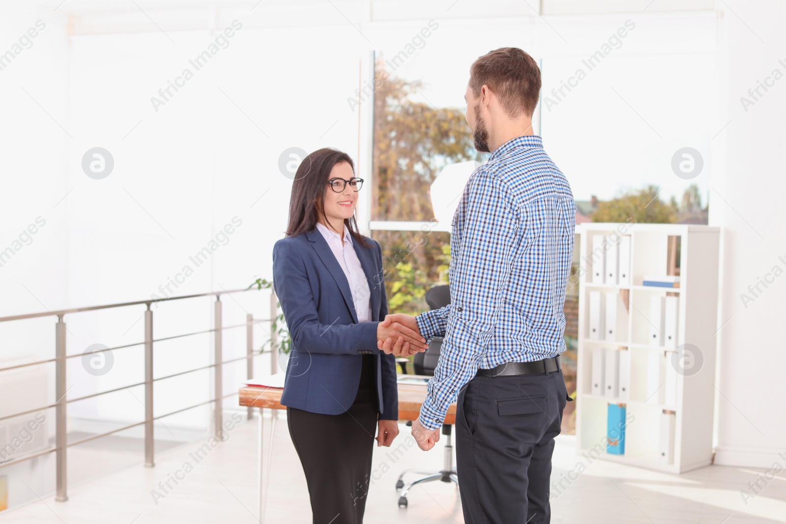 Photo of Human resources manager shaking hands with applicant during job interview in office