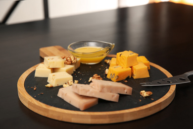 Different types of delicious cheeses, walnuts and honey on table, closeup