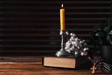 Photo of Rosary beads, Bible, burning candle and willow branches on wooden table. Space for text