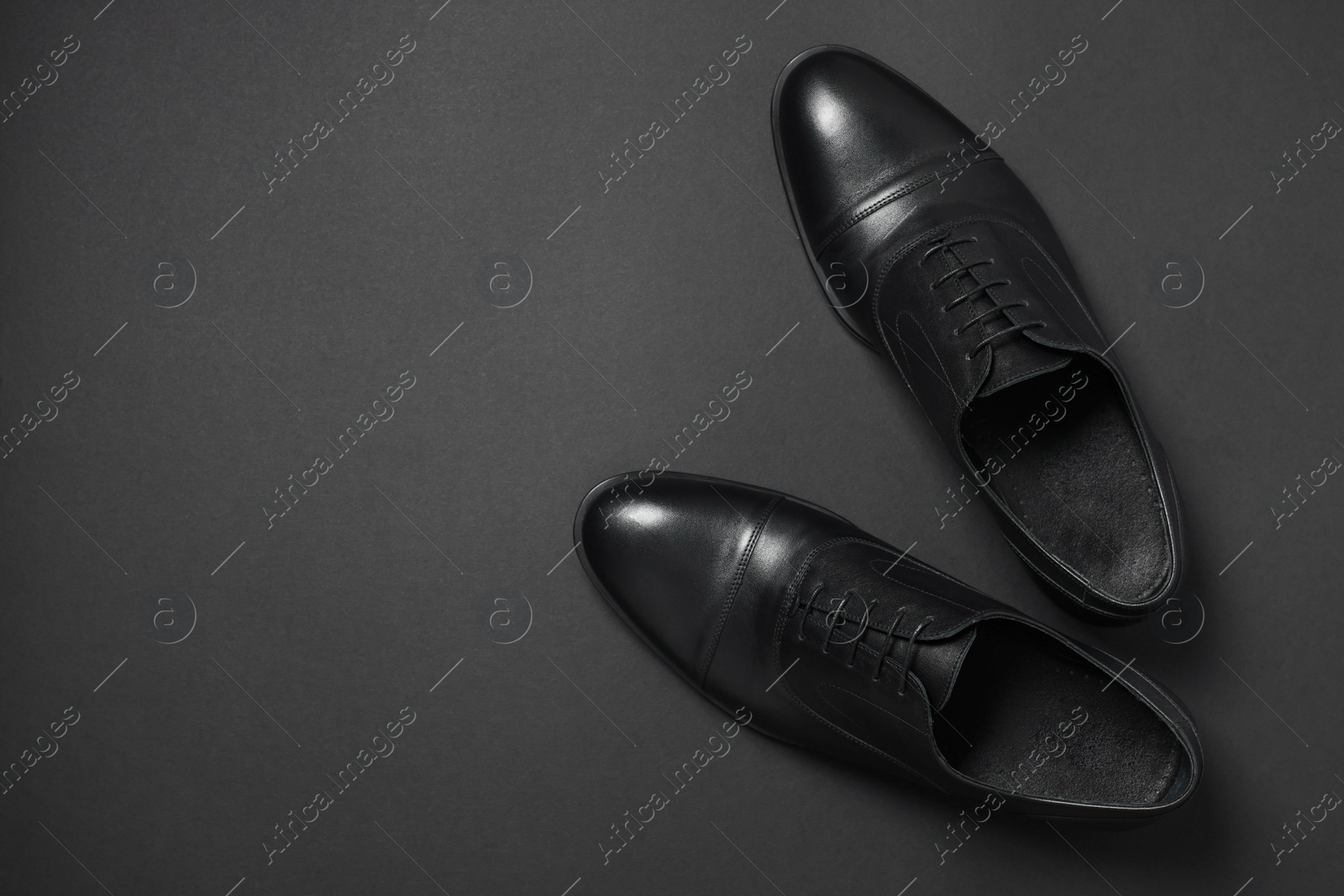 Photo of Pair of leather men shoes on black background, top view. Space for text