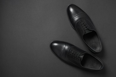 Photo of Pair of leather men shoes on black background, top view. Space for text