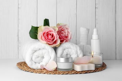 Photo of Composition with different spa products, roses and candle on white table against wooden background