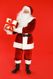 Photo of Authentic Santa Claus with gift box on red background