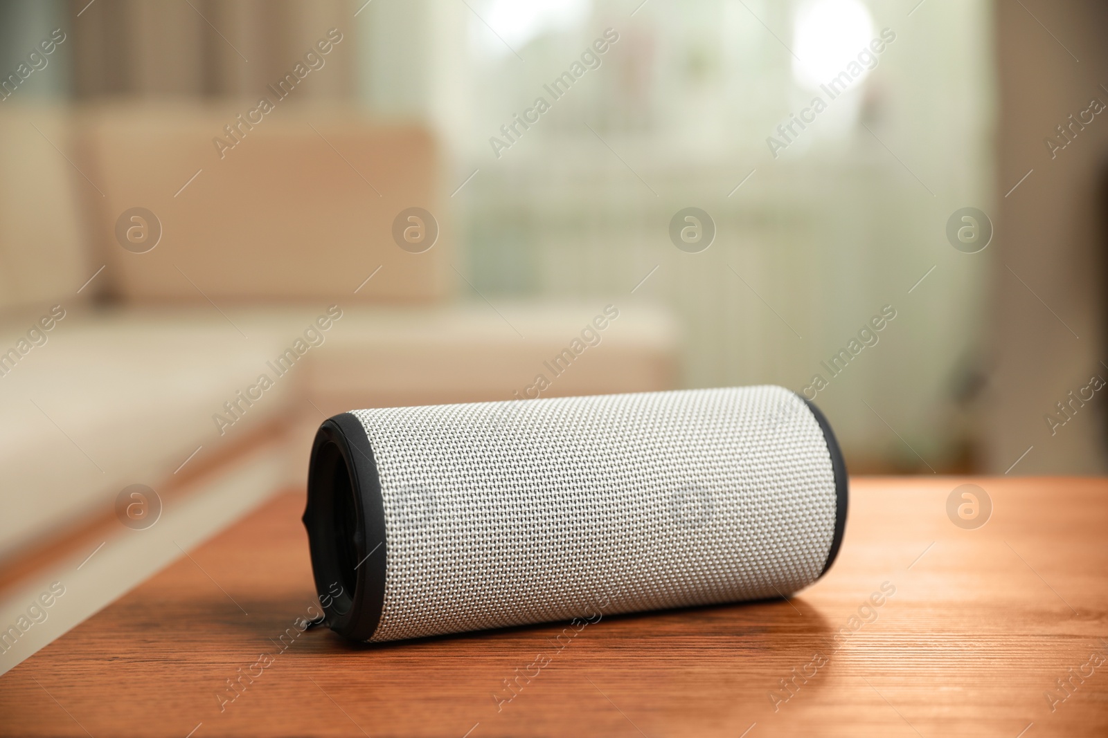 Photo of Portable bluetooth speaker on wooden table indoors. Audio equipment