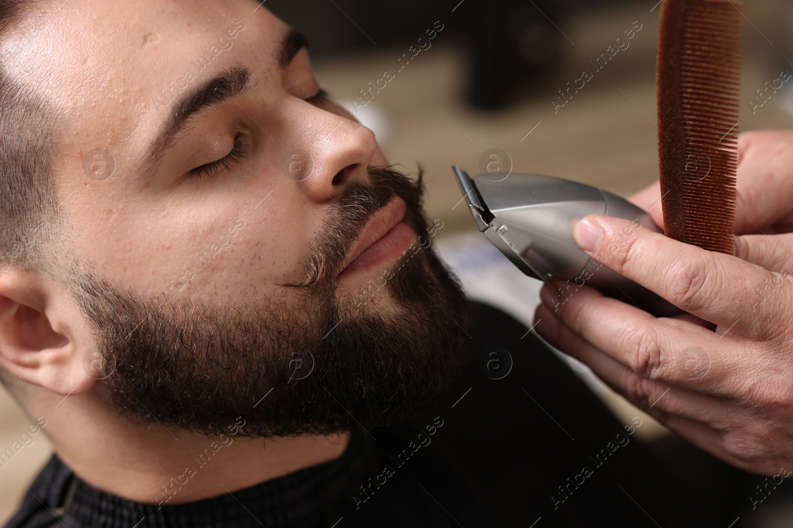 Photo of Professional barber trimming client's mustache in barbershop, closeup