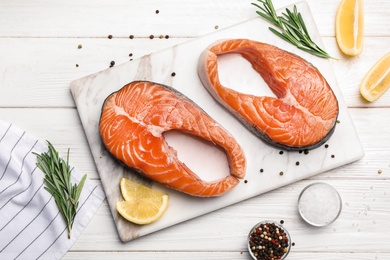 Flat lay composition with fresh salmon steaks on white wooden table