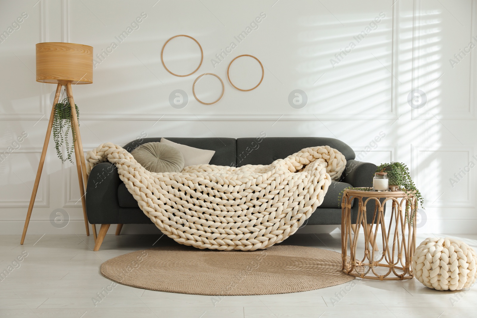 Photo of Soft chunky knit blanket on sofa in living room. Interior design