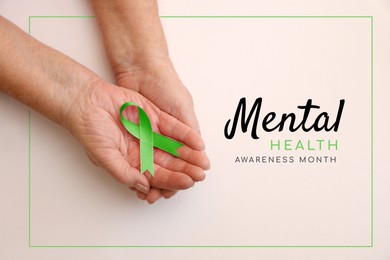 Image of World Mental Health Day. Woman holding green ribbon on white background, top view