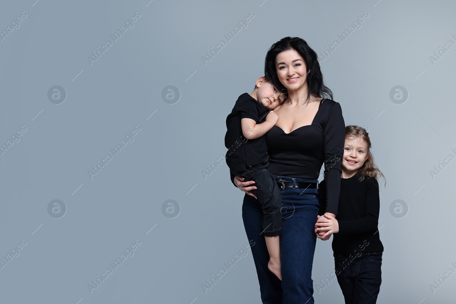 Photo of Little children with their mother on grey background. Space for text