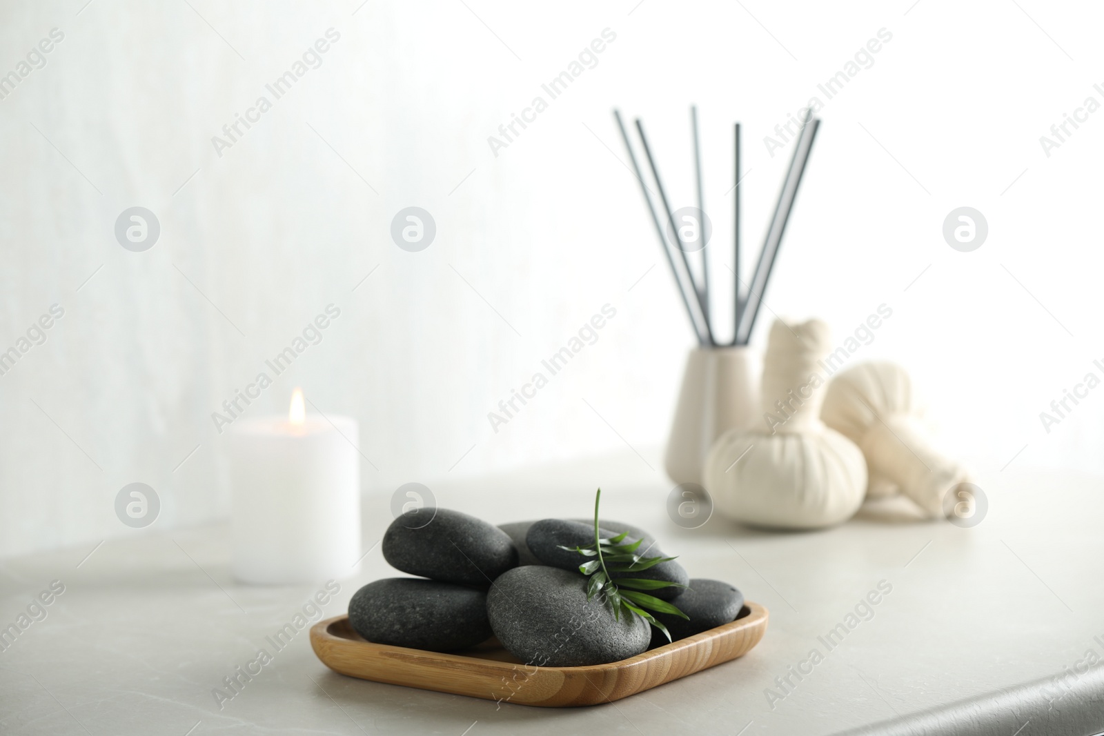 Photo of Spa stones and green leaf on light grey table