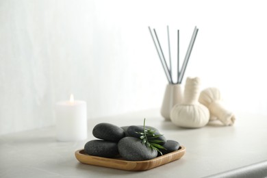 Photo of Spa stones and green leaf on light grey table