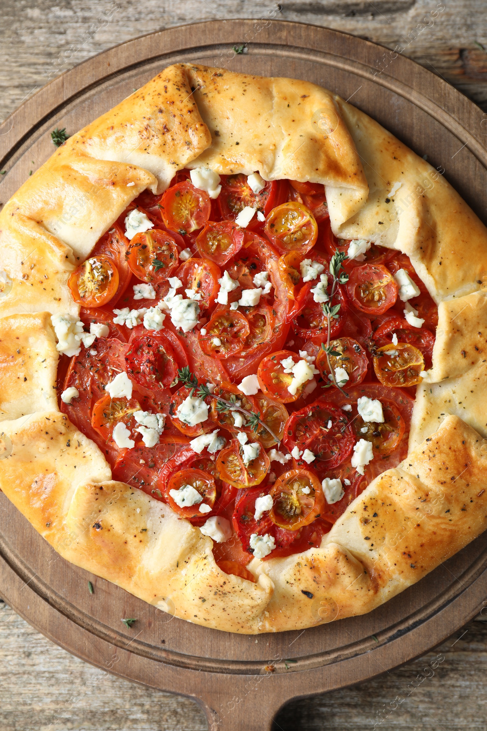 Photo of Tasty galette with tomato, thyme and cheese (Caprese galette) on wooden table, top view