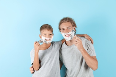 Photo of Father and son shaving together on color background