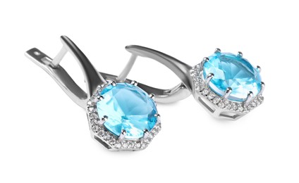 Photo of Elegant silver earrings with light blue gemstones isolated on white. Luxury jewelry
