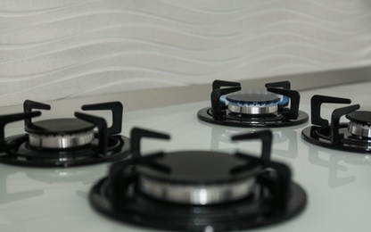 Photo of Gas burners with blue flame on modern stove